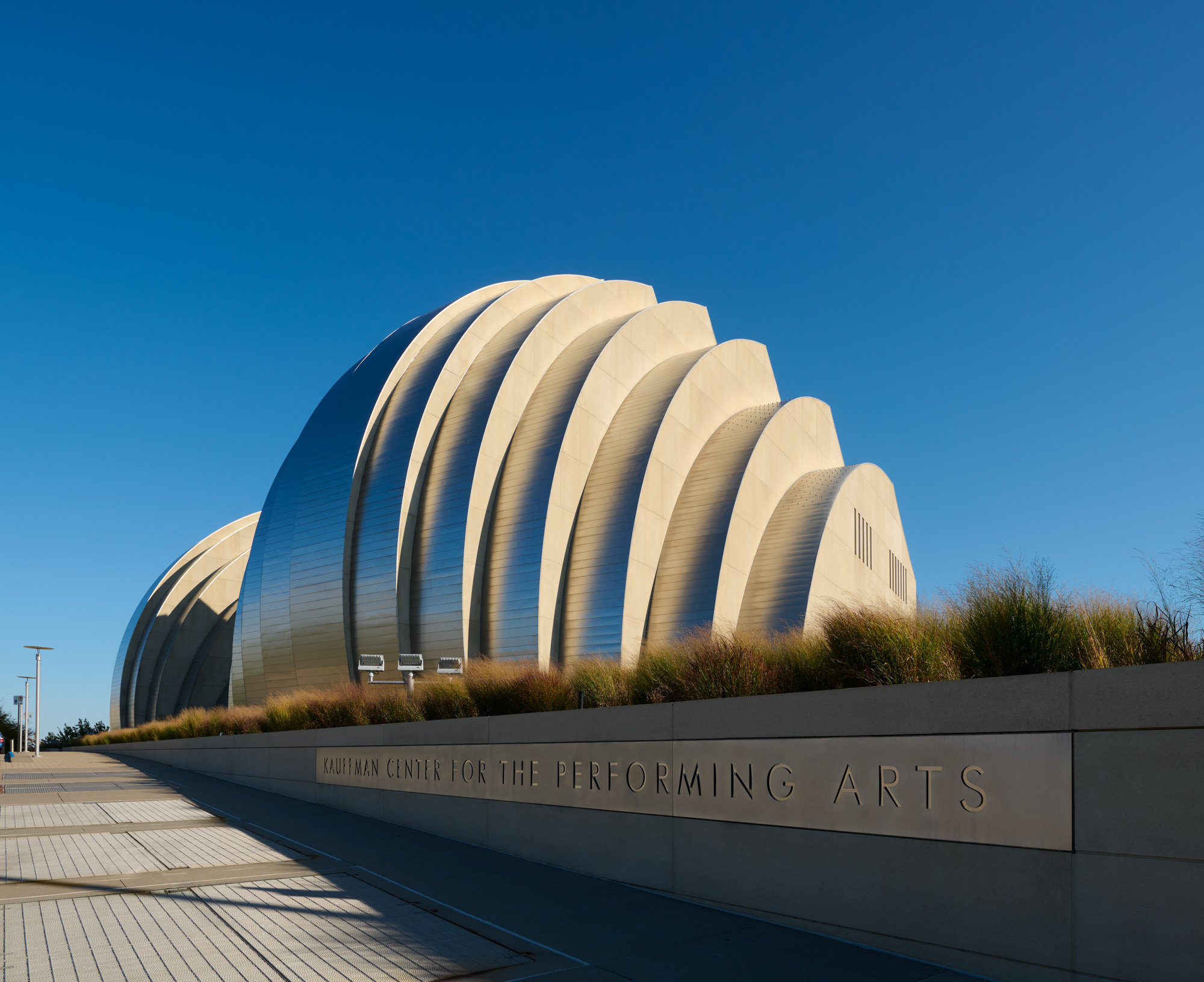 The Kauffman Center for the Performing Arts in Kansas City, Missouri, showcases its unique shell-like architectural design under a clear blue sky. This renowned Performing Arts Center in Kansas City stands as a testament to innovative design and cultural enrichment.