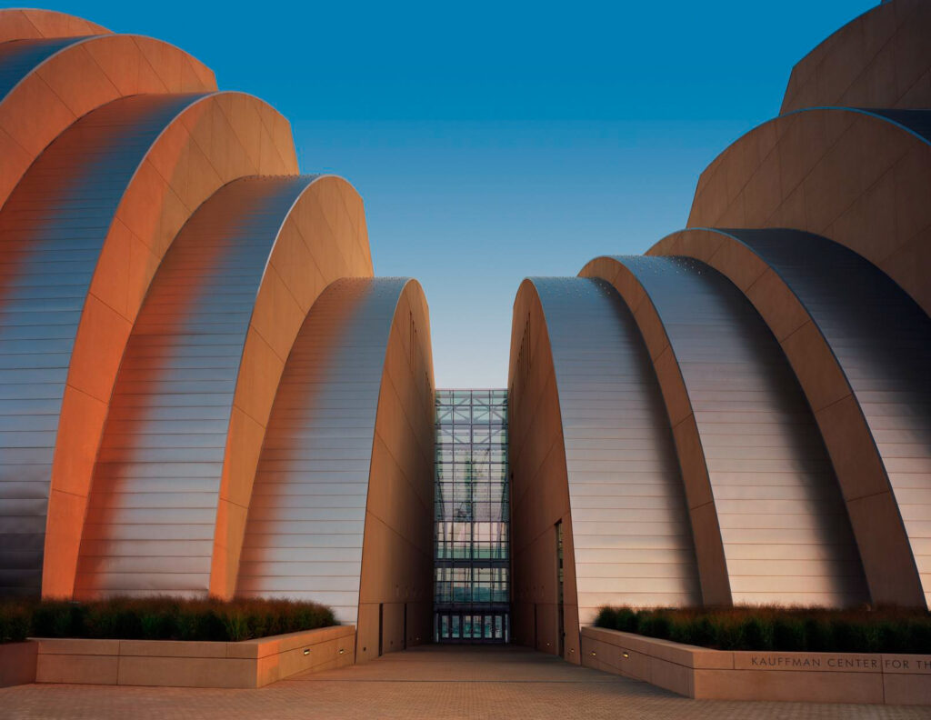 Exterior view of the Kauffman Center for the Performing Arts during sunset, showcasing its distinctive curved architectural design. Enhance your visit by exploring volunteer opportunities in Kansas City while you're here.