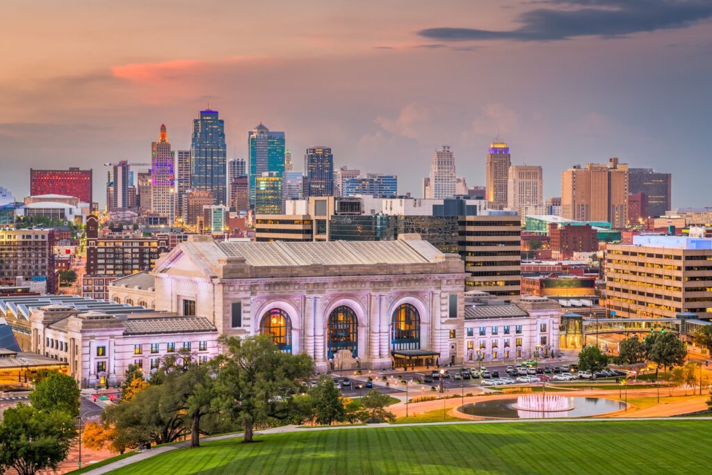 Panoramic view of Kansas City skyline at sunset with Union Station in the foreground, various skyscrapers in the background, and dining near Kauffman Center offering a perfect evening retreat.