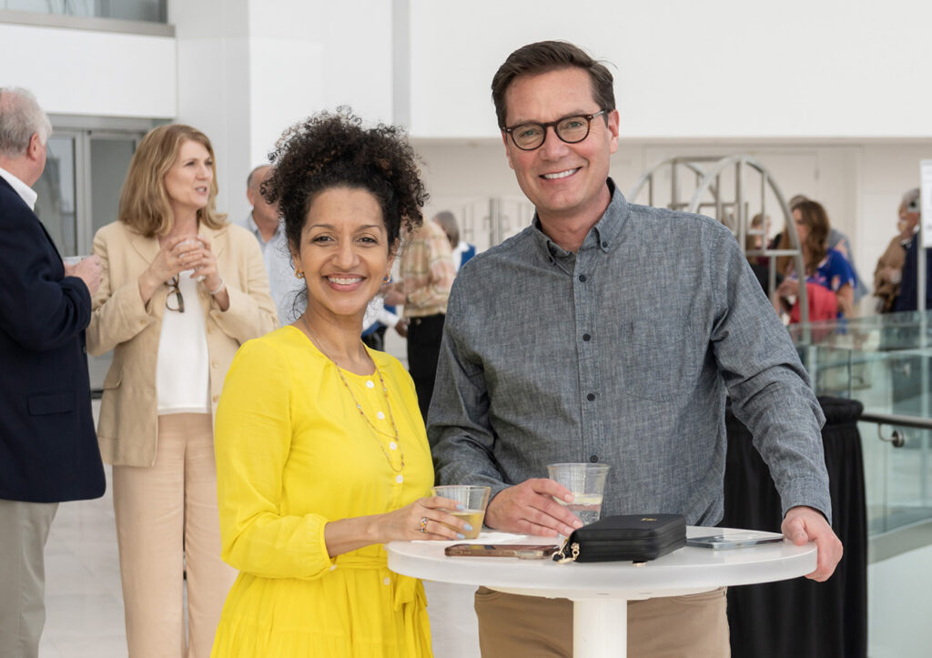 Wome in yellow dress and man wearing glasses smiling at an event out on date night at the Kauffman Center for thing to do in Kansas City for couples. Photo by Don Ipock.